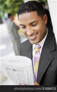 Close-up of a businessman reading a newspaper and smiling