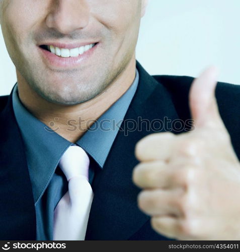 Close-up of a businessman showing thumbs up sign and smiling