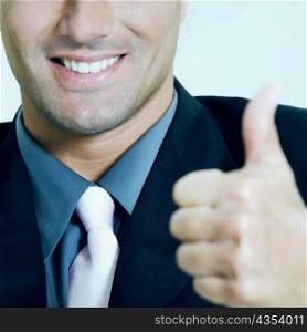Close-up of a businessman showing thumbs up sign and smiling