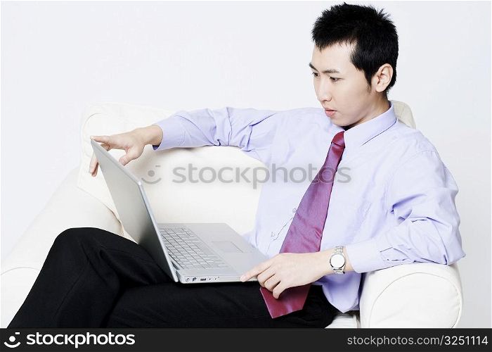 Close-up of a businessman sitting in an armchair and using a laptop