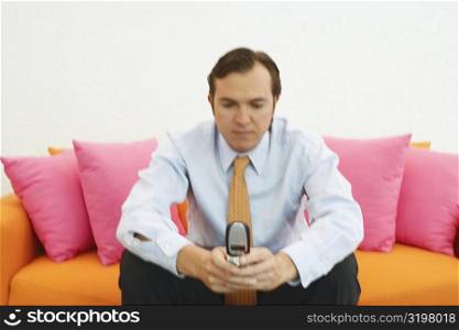 Close-up of a businessman sitting on a couch and using a mobile phone