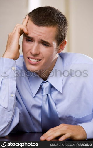 Close-up of a businessman sitting with his hand on his temple