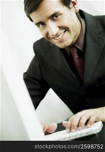 Close-up of a businessman smiling and working on a laptop