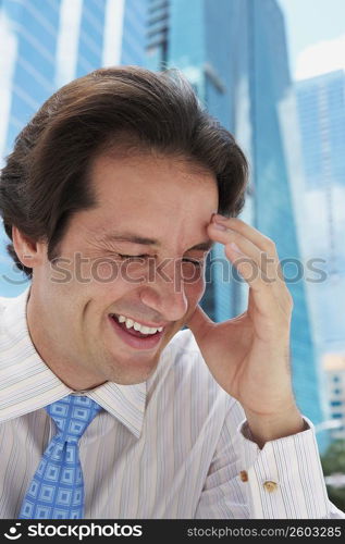 Close-up of a businessman smiling with his hand on his forehead