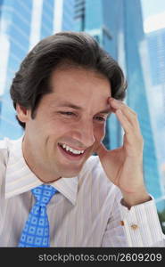 Close-up of a businessman smiling with his hand on his forehead