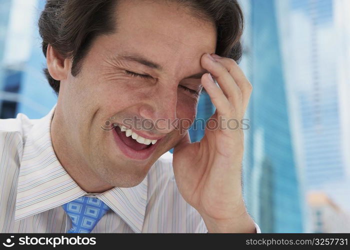 Close-up of a businessman smiling with his hand on his forehead