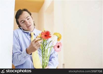 Close-up of a businessman talking on a mobile phone and holding a bunch of flowers