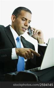 Close-up of a businessman talking on a mobile phone and using a laptop