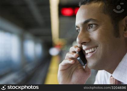 Close-up of a businessman talking on a mobile phone at a subway station