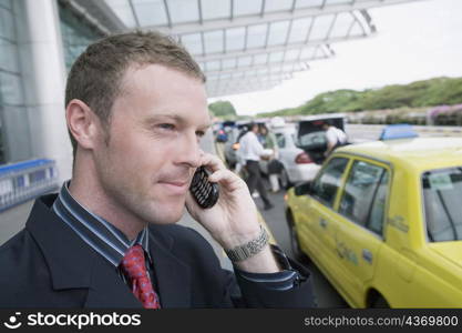 Close-up of a businessman talking on a mobile phone outside an airport