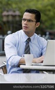 Close-up of a businessman thinking while using a laptop