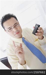 Close-up of a businessman using a calculator and thinking