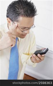 Close-up of a businessman using a calculator and thinking