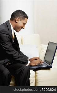 Close-up of a businessman using a laptop on a couch