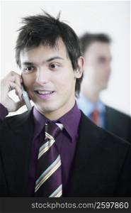 Close-up of a businessman using a mobile phone with another businessman behind him