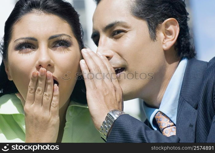 Close-up of a businessman whispering into a businesswoman&acute;s ear