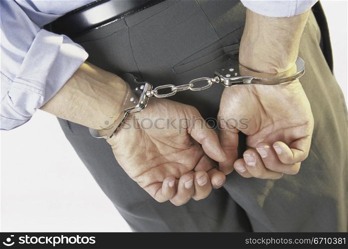 Close-up of a businessman with his hands handcuffed behind his back