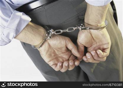 Close-up of a businessman with his hands handcuffed behind his back