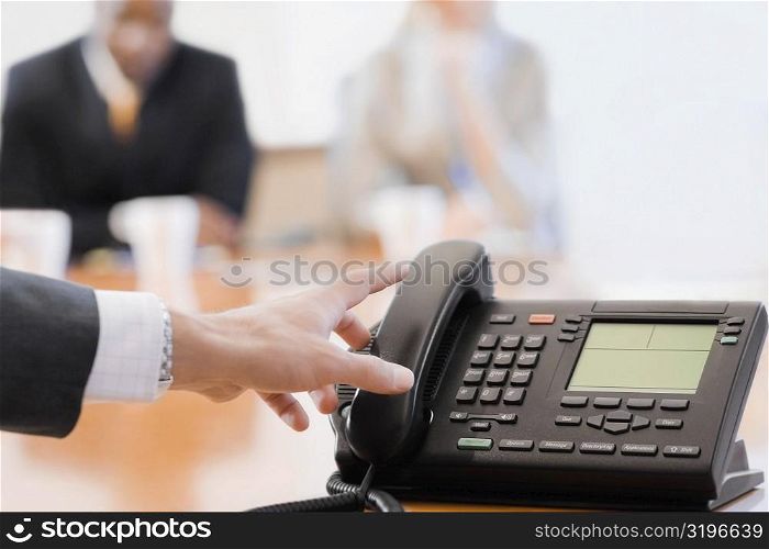 Close-up of a businesswoman&acute;s hand reaching to a conference phone receiver