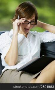 Close-up of a businesswoman adjusting her eyeglasses and reading a file