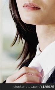 Close-up of a businesswoman adjusting her tie