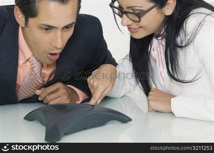 Close-up of a businesswoman and a businessman using a conference phone