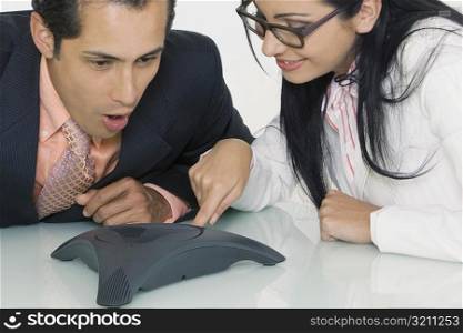 Close-up of a businesswoman and a businessman using a conference phone