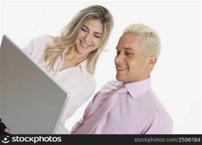 Close-up of a businesswoman and a businessman using a laptop and smiling
