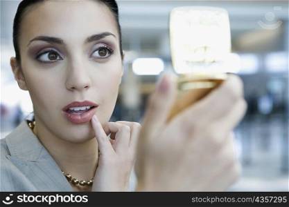 Close-up of a businesswoman checking her lips in a hand mirror