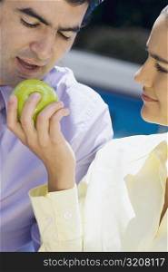Close-up of a businesswoman feeding a green apple to a businessman