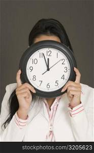 Close-up of a businesswoman hiding her face with a clock