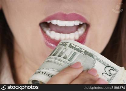 Close-up of a businesswoman holding a bundle of dollar bills near her mouth