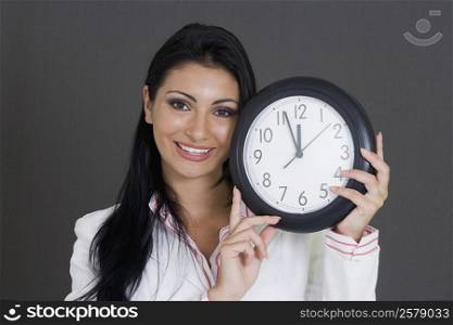 Close-up of a businesswoman holding a clock and smiling
