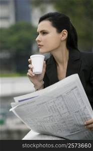 Close-up of a businesswoman holding a newspaper and thinking