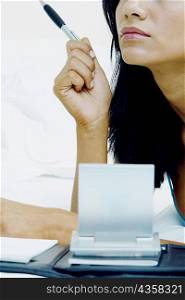Close-up of a businesswoman holding a pen and thinking