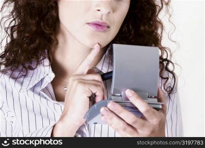 Close-up of a businesswoman holding a pen with a calculator and thinking