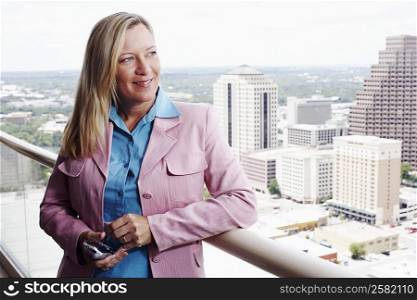 Close-up of a businesswoman holding a personal data assistant with a city in the background