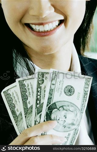 Close-up of a businesswoman holding American dollar bills and smiling