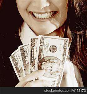Close-up of a businesswoman holding dollar bills and smiling