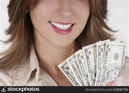 Close-up of a businesswoman holding fanned out dollar bills and smiling