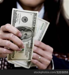 Close-up of a businesswoman holding one hundred dollar bills