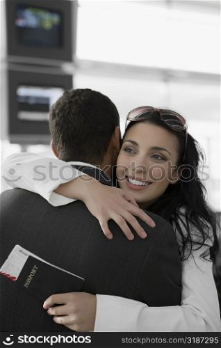 Close-up of a businesswoman hugging a businessman at an airport