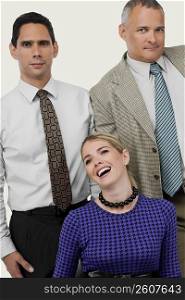 Close-up of a businesswoman laughing with two businessmen standing behind her