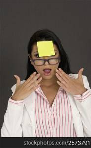 Close-up of a businesswoman looking shocked with an adhesive note in front of her forehead
