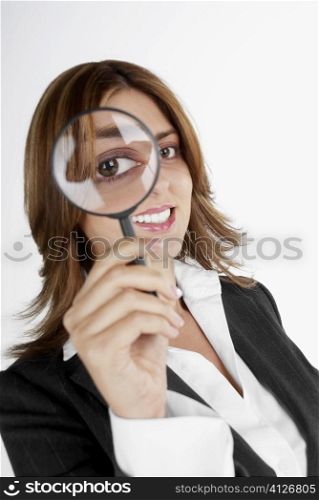 Close-up of a businesswoman looking through a magnifying glass