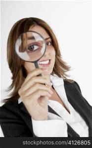 Close-up of a businesswoman looking through a magnifying glass