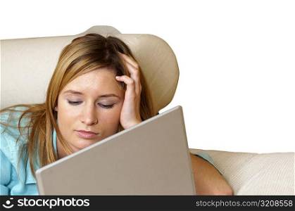 Close-up of a businesswoman lying on a couch in front of a laptop