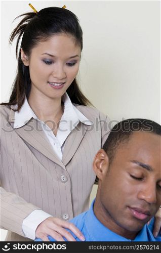 Close-up of a businesswoman massaging a businessman&acute;s shoulder