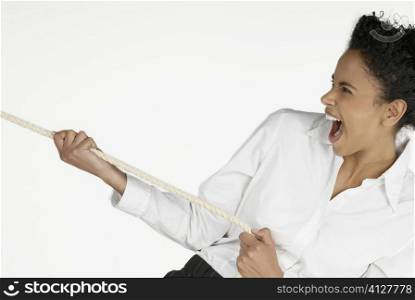 Close-up of a businesswoman pulling a rope and laughing