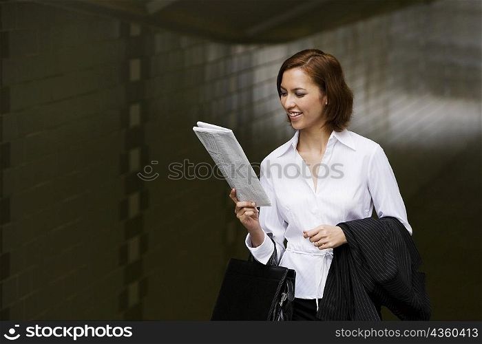 Close-up of a businesswoman reading a newspaper and smiling